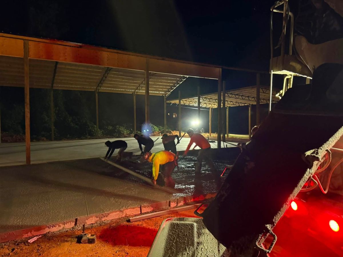 Concrete being placed under a pole barn at night