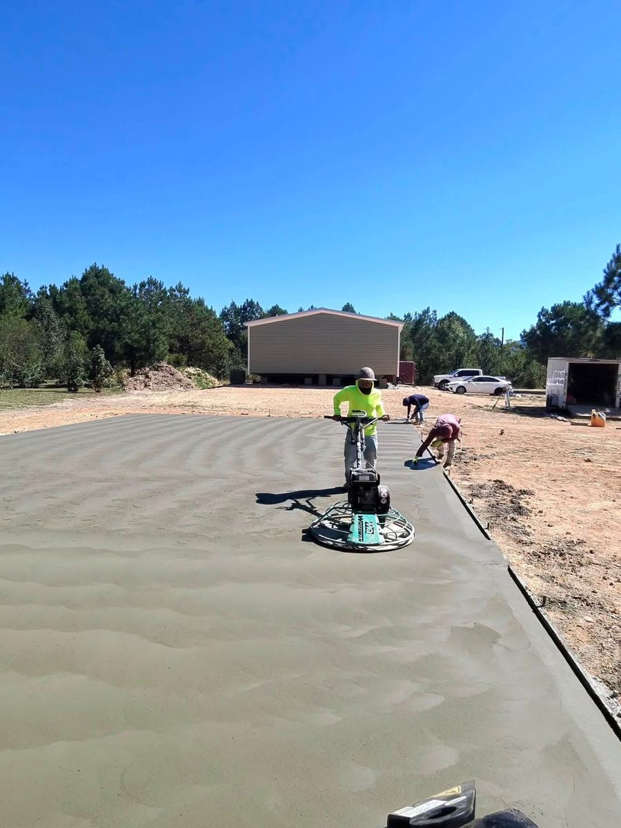 A crew member running a power trowel over fresh concrete