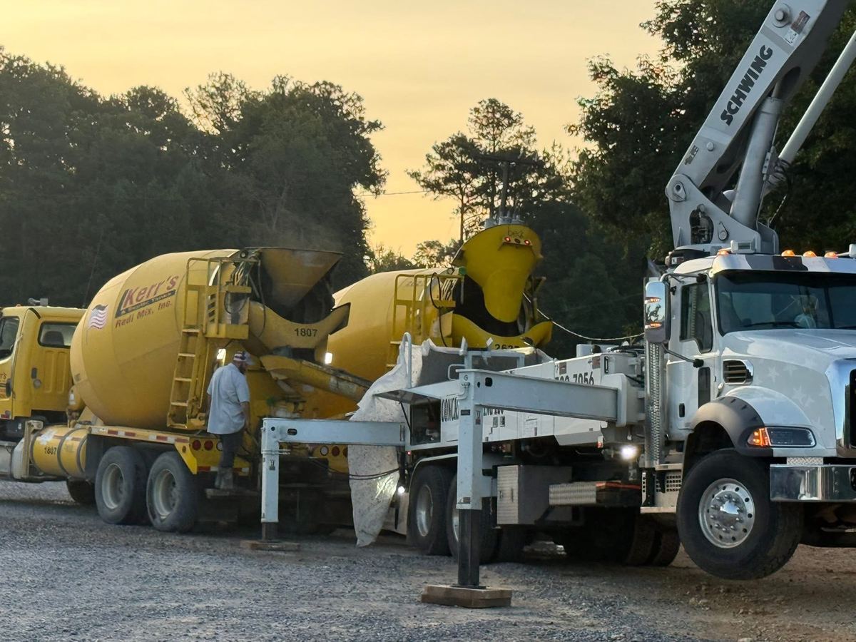 Two concrete mixer trucks and a pump truck lined up on a job